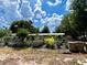 A cozy single-story home surrounded by lush greenery, featuring a fenced yard and a clear, blue sky backdrop at 40431 Country Rd, Eustis, FL 32736