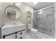 Bright bathroom featuring a modern vanity, round mirror, and glass-enclosed shower with decorative marble-patterned tile at 410 W Seminole Ave, Eustis, FL 32726