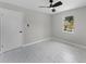 Neutral bedroom with modern lighting, tile floors, and a large window offering a view of the backyard at 410 W Seminole Ave, Eustis, FL 32726