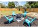 A backyard seating area with a modern fire pit, Adirondack chairs, string lights, and a wooden fence at 410 W Seminole Ave, Eustis, FL 32726