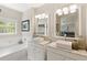 Bright bathroom with double sink vanity, large mirrors, garden tub and neutral walls at 476 Water St, Celebration, FL 34747