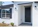 Home's black front door with dark trim, modern outdoor lighting, and textured white exterior walls at 509 St. Johns Ct, Poinciana, FL 34759