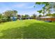 Expansive backyard featuring lush green grass and mature trees, play structure and room for outdoor activities at 5384 Barton Dr, Orlando, FL 32807