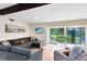 Open-concept living room featuring modern decor, TV, view of lush backyard through sliding glass doors and wood beam at 5384 Barton Dr, Orlando, FL 32807