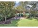 A tranquil backyard retreat with a cozy pergola surrounded by lush landscaping and a verdant lawn at 612 Golden Dawn, Apopka, FL 32712