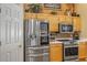Modern kitchen featuring stainless steel appliances, light wood cabinets, and adjacent white pantry door at 612 Golden Dawn, Apopka, FL 32712