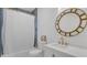 Bright bathroom features white cabinets, a round mirror, and a shower with blue accent tiles at 708 S Laurel Ave, Sanford, FL 32771