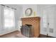 Close up on a vintage brick fireplace with tile hearth, hardwood floors and white sheer curtains at 708 S Laurel Ave, Sanford, FL 32771