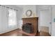 Close up on a vintage brick fireplace with tile hearth, hardwood floors and white sheer curtains at 708 S Laurel Ave, Sanford, FL 32771