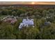Sunset aerial view of a modern home featuring a pool, manicured lawn, and lush greenery at 7615 Se 12Th Cir, Ocala, FL 34480