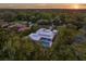 Sunset aerial view of a modern home featuring a pool, manicured lawn, and lush greenery at 7615 Se 12Th Cir, Ocala, FL 34480
