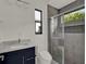 Bathroom featuring a blue vanity, toilet, and glass-enclosed shower with gray textured tile surround at 7615 Se 12Th Cir, Ocala, FL 34480