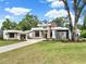 Modern home with a lush green lawn, a long driveway, and sleek architectural details at 7615 Se 12Th Cir, Ocala, FL 34480