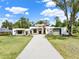 Modern home with stone accents and a long driveway, set on a well-maintained lawn under a blue sky at 7615 Se 12Th Cir, Ocala, FL 34480