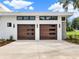 Two-car garage with modern wood doors and sleek exterior lighting fixtures at 7615 Se 12Th Cir, Ocala, FL 34480