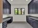 Bright laundry room with gray cabinetry, countertops, tile flooring, and a window view to the outdoors at 7615 Se 12Th Cir, Ocala, FL 34480