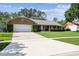 Brick ranch home with attached garage and concrete driveway, complemented by lush green lawn at 7618 Majestic Pine Ct, Orlando, FL 32819