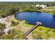 Aerial view of lake with a wooden pier extending into the water surrounded by lush greenery at 7618 Majestic Pine Ct, Orlando, FL 32819