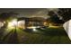 Night shot of a screened-in pool with beautiful underwater lighting, surrounded by lush lawn at 7618 Majestic Pine Ct, Orlando, FL 32819