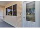 Close up of the glass-paneled front door and window, framed by light yellow siding at 8443 Sw 109Th Pl, Ocala, FL 34481