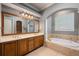 Bathroom with double sinks, large mirror, and a soaking tub at 8475 Eagles Loop Cir, Windermere, FL 34786