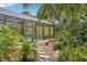 View of the screened pool from the garden path, showcasing the privacy and tranquility of the outdoor space at 98 Wisteria Dr, Longwood, FL 32779