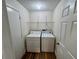 Functional laundry room with washer, dryer, shelving, and wood-look floors at 11725 Cuxham Dr, Orlando, FL 32837