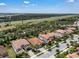 An aerial view of a neighborhood shows well-maintained homes with dark tile roofs, green trees, and a highway in the distance at 11741 Savona Way, Orlando, FL 32827