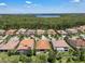 An aerial view shows beautiful neighborhood homes with dark tile roofs, green trees, and a lake in the distance at 11741 Savona Way, Orlando, FL 32827