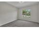 A bright, carpeted bedroom with a window showing an exterior view of the property and the surrounding neighborhood at 11741 Savona Way, Orlando, FL 32827