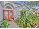 Close up of front entrance with double red doors, brick paver walkway and lush tropical foliage at 1181 Welch Hill Cir, Apopka, FL 32712