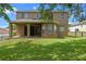 Exterior home view with a covered patio, sliding glass doors, and a large grassy yard at 12824 Cloverdale Ln, Clermont, FL 34711