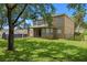 Large backyard featuring a grassy lawn, mature trees, and a covered patio at 12824 Cloverdale Ln, Clermont, FL 34711