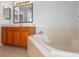 Well-lit bathroom featuring a soaking tub with tile surround and vanity sink at 12824 Cloverdale Ln, Clermont, FL 34711