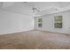 Spacious main bedroom featuring a ceiling fan, tray ceiling, and large windows at 12824 Cloverdale Ln, Clermont, FL 34711