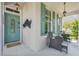 Inviting front porch featuring stylish seating, lantern lighting, and a vibrant turquoise door at 13822 Darchance Rd, Windermere, FL 34786