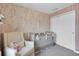Charming Bedroom with floral wallpaper, soft chair, and light-grey crib, perfect for a baby's room at 14250 Sapelo Beach Dr, Orlando, FL 32827