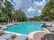 Large outdoor pool with sun loungers and umbrellas, surrounded by lush landscaping at 14835 Old Thicket Trce, Winter Garden, FL 34787