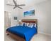 Bright bedroom with a ceiling fan and blue bedspread complemented by stylish pillows at 15049 Canopy Cover Dr, Winter Garden, FL 34787