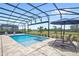Relaxing lounge chairs sit by a sparkling pool and spa under a screened enclosure with a lovely view at 15049 Canopy Cover Dr, Winter Garden, FL 34787