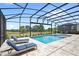Relaxing lounge chairs sit by a sparkling pool and spa under a screened enclosure with a beautiful view at 15049 Canopy Cover Dr, Winter Garden, FL 34787
