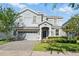 Charming two-story home showcasing lush landscaping and a paver driveway at 1520 Mulligan Blvd, Davenport, FL 33896