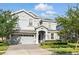 Charming two-story home showcasing lush landscaping and a paver driveway at 1520 Mulligan Blvd, Davenport, FL 33896