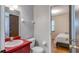 Bathroom featuring a red vanity, mirror, toilet, and doorway leading to a bedroom with a window at 1525 Jaguar Cir, Apopka, FL 32712