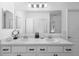 Bright bathroom offers a double vanity with white cabinets and a large mirror at 15356 White Tail Loop, Mascotte, FL 34753