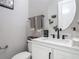 Stylish half bathroom features white vanity with black fixtures and a decorative round mirror at 200 Azure Mist Way, Daytona Beach, FL 32124