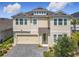 Charming two-story home with a tan exterior, brick driveway, and lush landscaping at 200 Azure Mist Way, Daytona Beach, FL 32124