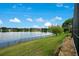 Scenic lake view with lush green lawn, metal fencing, and mature trees creating a serene and picturesque outdoor space at 529 Quail Down Dr, Debary, FL 32713