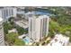 An aerial view of a white high-rise condominium building with a blue pool, set amid lush greenery and a picturesque lake at 530 E Central Blvd # 406, Orlando, FL 32801