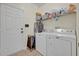 Bright laundry room with white washer and dryer, storage shelving, and convenient access door at 533 Pickfair Ter, Lake Mary, FL 32746